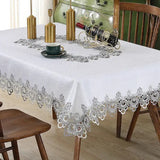 White and grey lace embroidery tablecloth with floral patterns on a dining table. Elegant and waterproof, perfect for home and event decor.