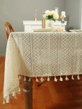 Beige wave triangular lace tablecloth with tassels for elegant dining table decoration.