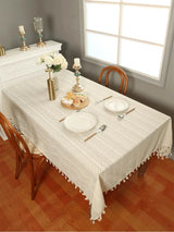 Beige lace tablecloth with a wave pattern and tassels for a sophisticated dining setup