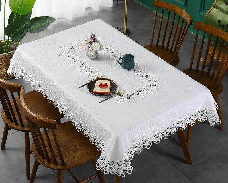 Ivory lace embroidery tablecloth with floral patterns on a dining table. Elegant and waterproof, suitable for weddings and home decor.