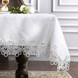 White lace embroidery tablecloth with intricate floral patterns and scalloped edges. Ideal for dining tables, weddings, and special occasions.