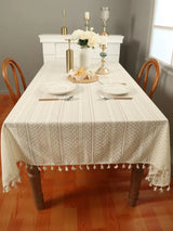 Stylish beige lace tablecloth with a wave pattern and tassels, perfect for home decor.